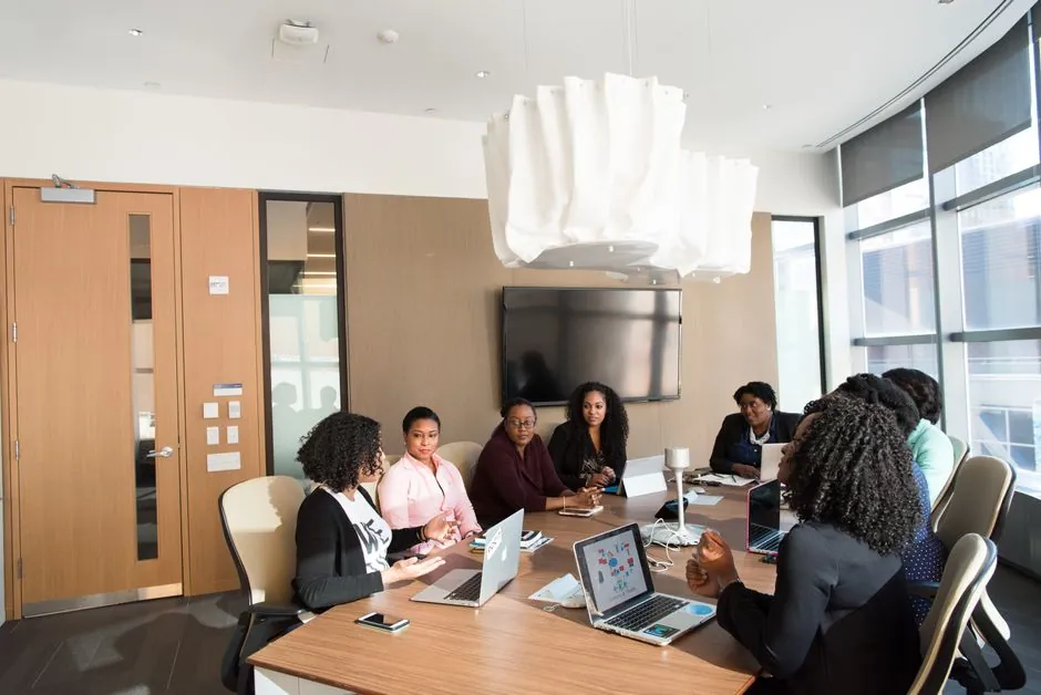 Colleagues seated around a table looking at a laptop in a meeting room