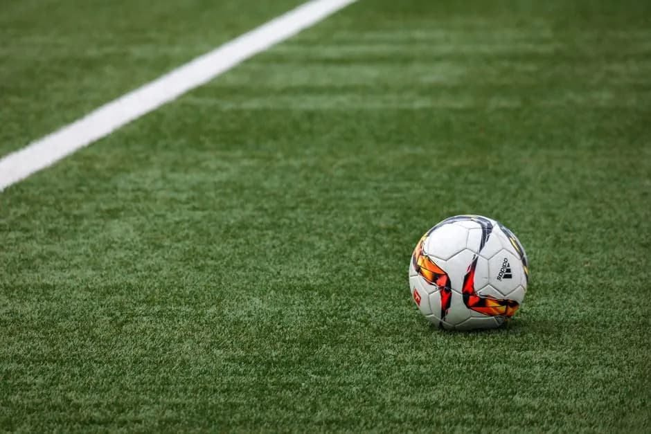 A football on the centre spot of a grass pitch