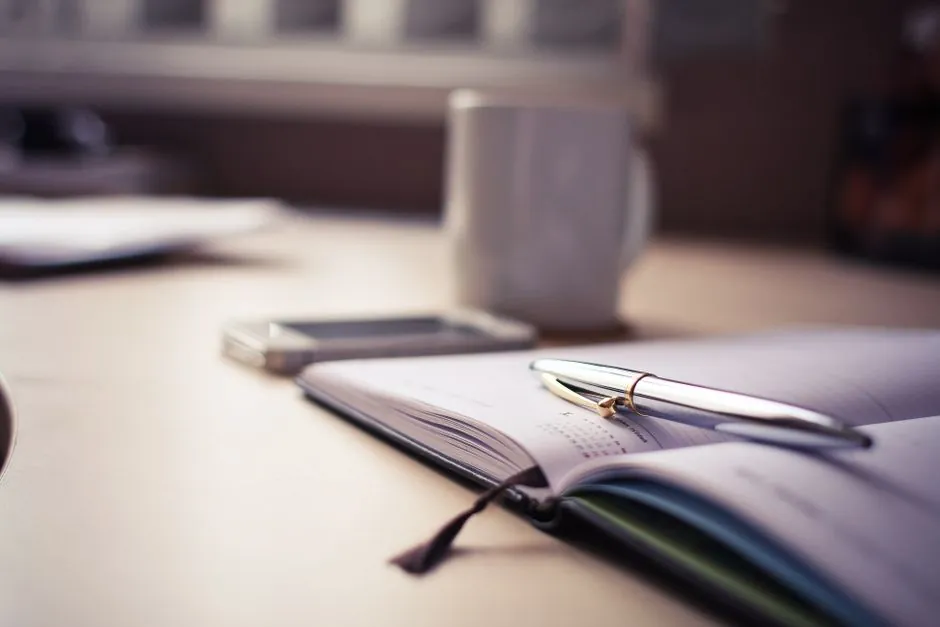 A postcard and pen resting on a wooden table
