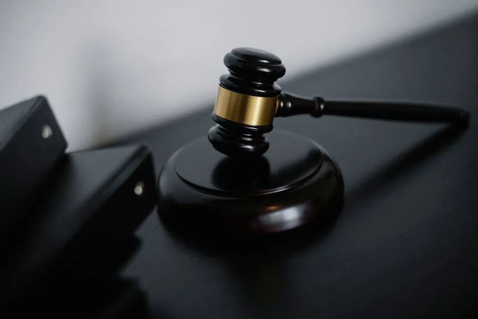 A wooden gavel resting on a desk beside legal documents